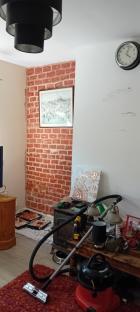 A room with a painted brick wall, a vacuum cleaner, and paint trays.