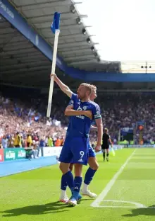 Soccer player celebrating a goal, holding a corner flag.