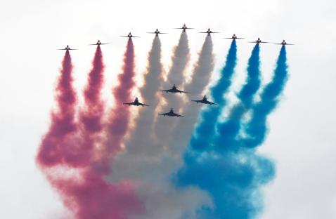 Military flypast over London, leaving red, white, and blue smoke trails.
