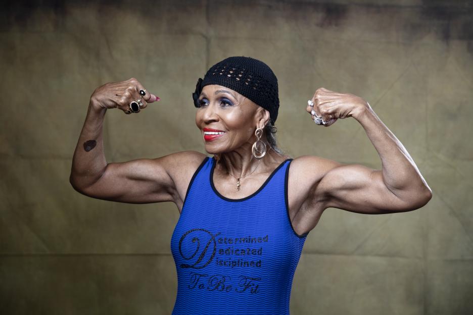 Portrait of Ernestine Shepherd, a bodybuilder, flexing her biceps.