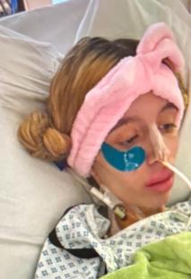 Woman in hospital bed with medical tubes.