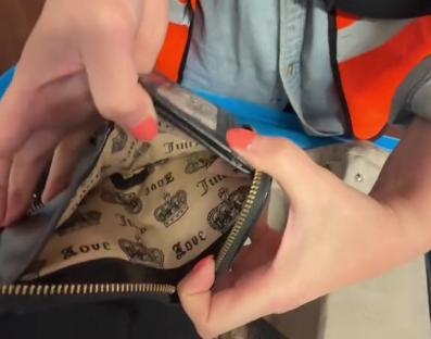 Close-up of a person holding open a Juicy Couture bag.