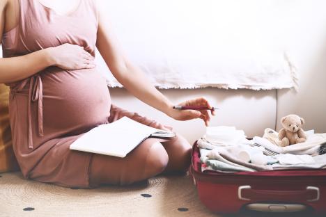 Pregnant woman packing a suitcase for the hospital.