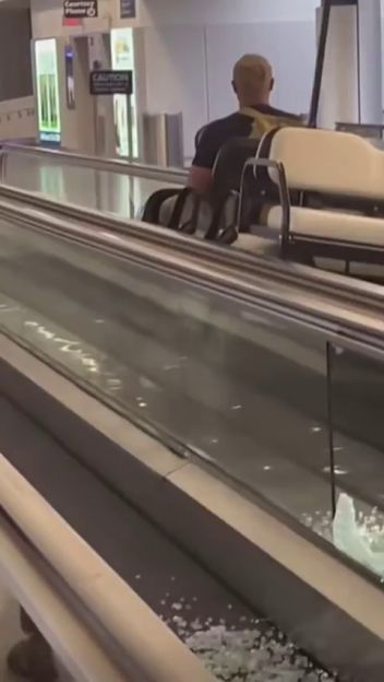 Shattered glass on a moving walkway with a man in a golf cart.