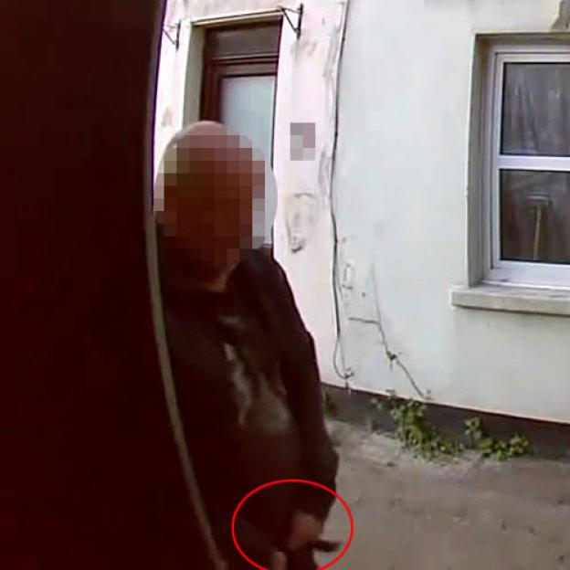 Video still of a man defecating on a doorstep.
