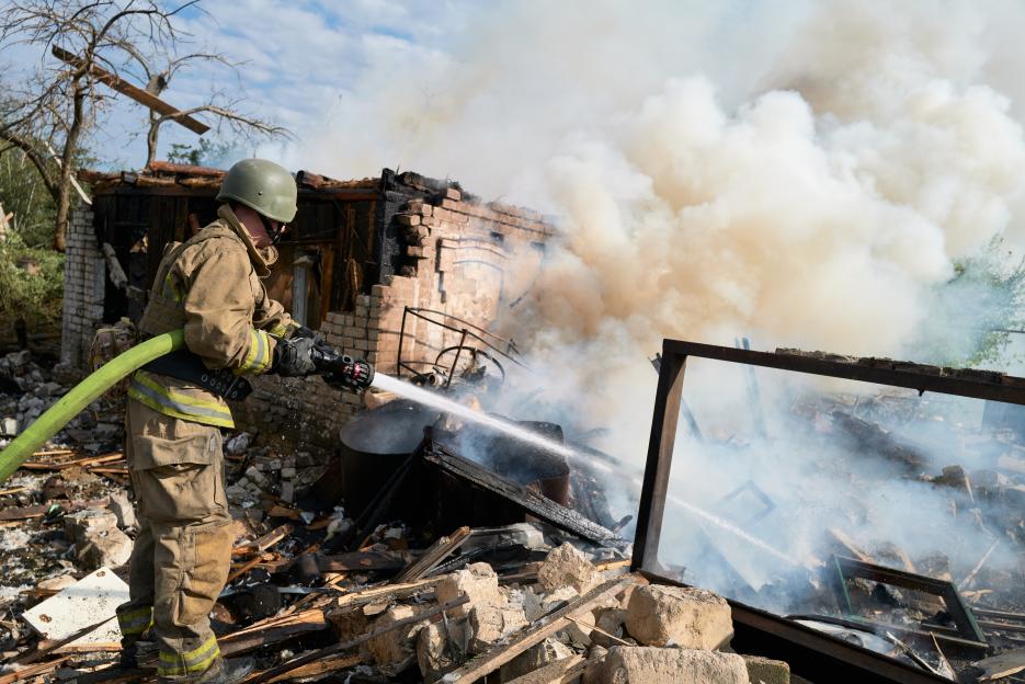 Firefighter extinguishing a burning house in Iverske, Ukraine.