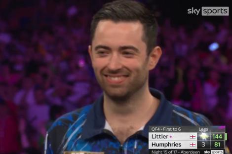 Smiling darts player, Littler, during a match.