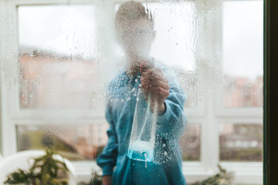 Portrait of a Window Cleaner Looking Through and Cleaning a Window