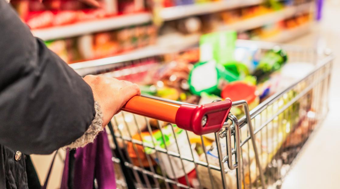 Woman's hand on supermarket trolley handle.