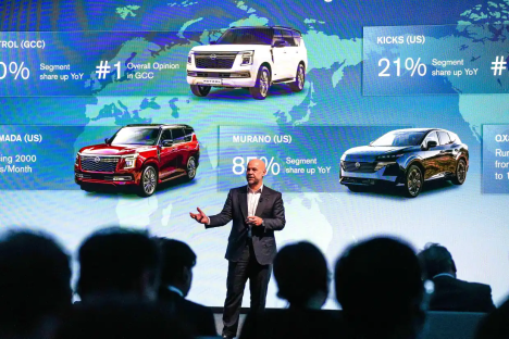 Presenter showing sales data for Nissan vehicles on a screen.