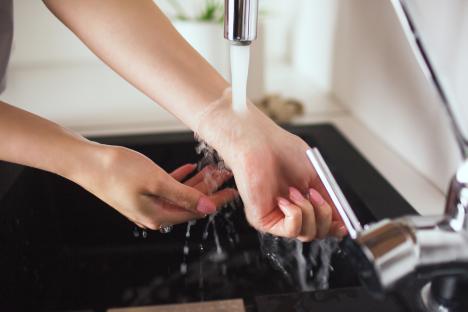 Woman washing her hands under running water.
