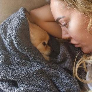 Woman cuddling her dog under a blanket.