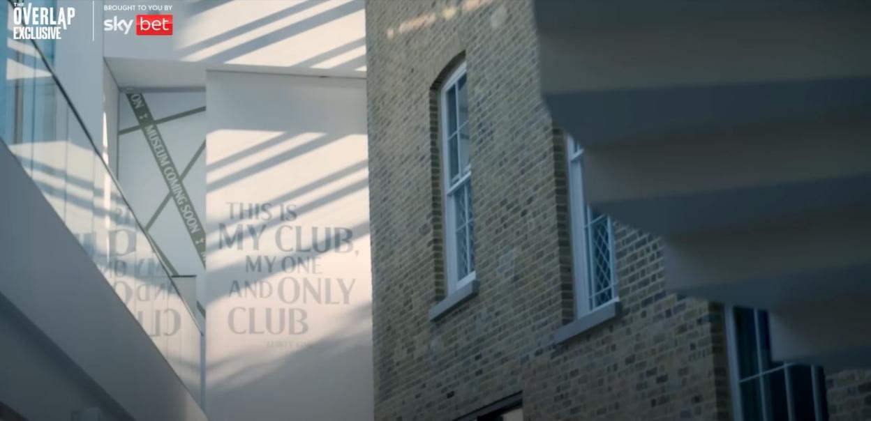 Premier League stadium interior with "This is my club, my one and only club" text on the wall.