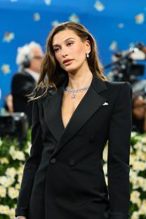 Hailey Bieber at the Met Gala in a black tuxedo jacket and sheer black tights.