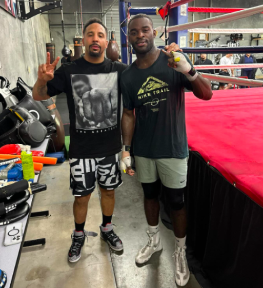 Two men posing in a boxing gym.