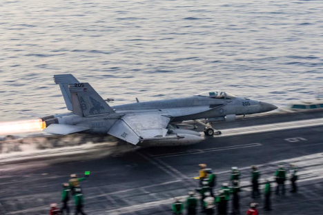 Navy F/A-18 Super Hornet launching from aircraft carrier.