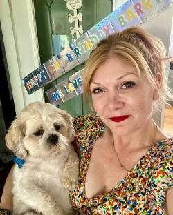 Woman holding a small dog, celebrating the dog's second birthday.