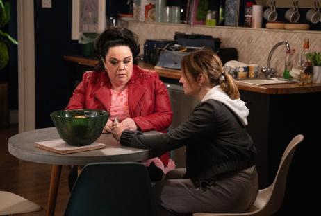 Two women sitting at a kitchen table, talking.