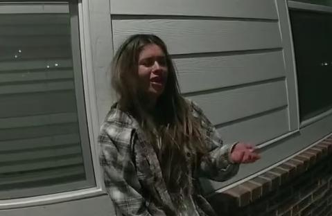 a woman in a plaid shirt is standing in front of a building .