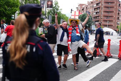 Manchester United fans crossing a street, watched by police.