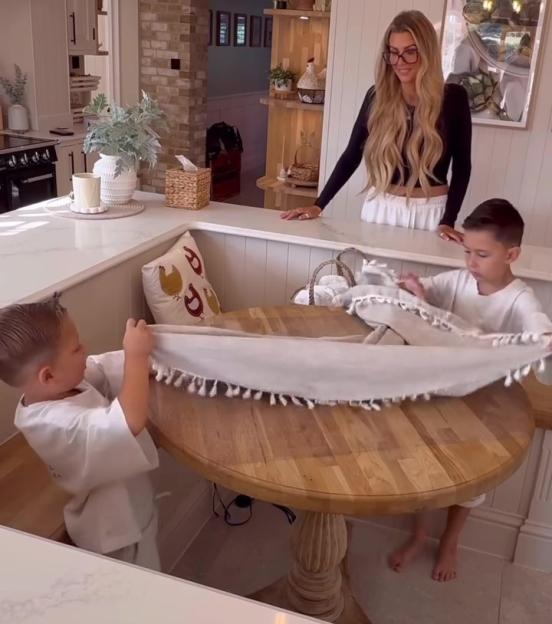 A woman and her two sons setting a table in a kitchen.