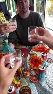 People toasting with shots at a table decorated with flowers and blood oranges.