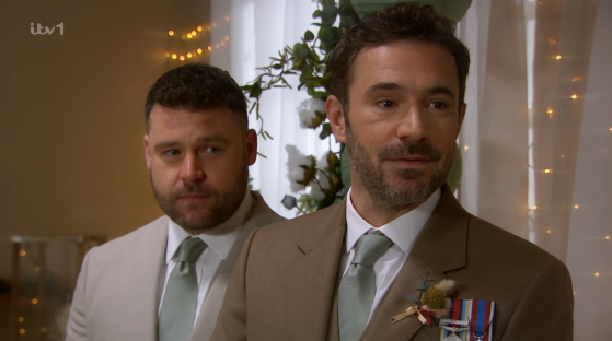 Screenshot of two men in suits at a wedding.