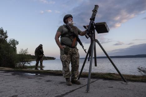 Volunteer soldier setting up a machine gun near a lake in Kyiv region, Ukraine.