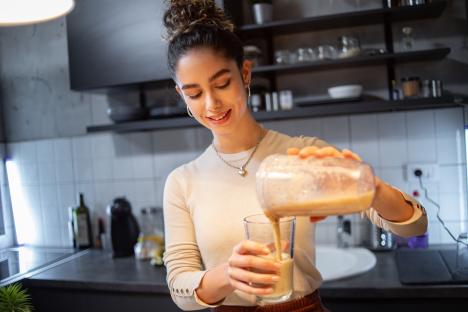 Woman pouring smoothie from blender into glass.