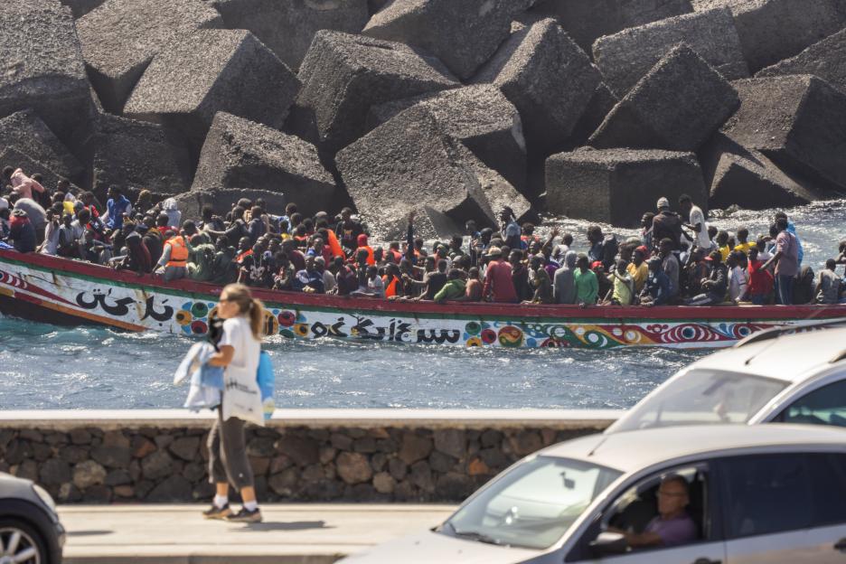Migrants arrive in a boat at a port.