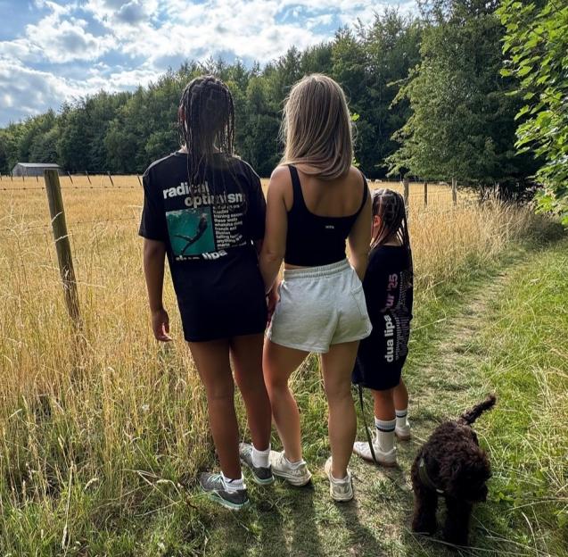 Katie Piper and her family with a small dog walking on a grassy path.