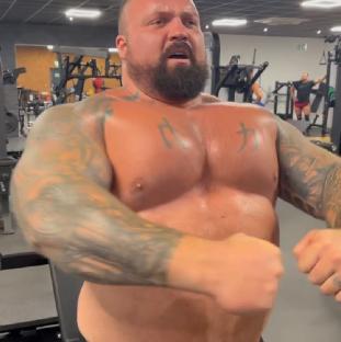 Eddie Hall flexing his muscles in a gym.
