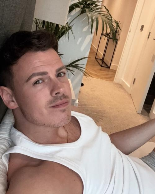 Man in white tank top relaxing indoors.