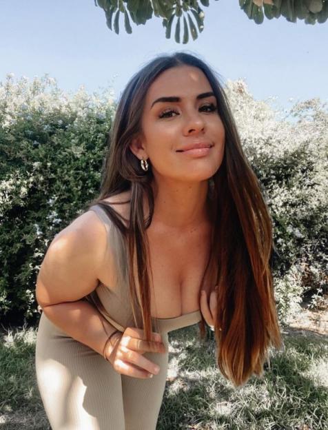 Woman in beige outfit posing outdoors.