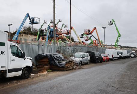 Aerial work platforms behind a fence at an industrial site.