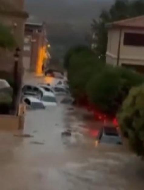 Flooded street with cars submerged in muddy water.