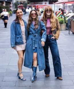 Three women in denim outfits posing outside a radio studio.