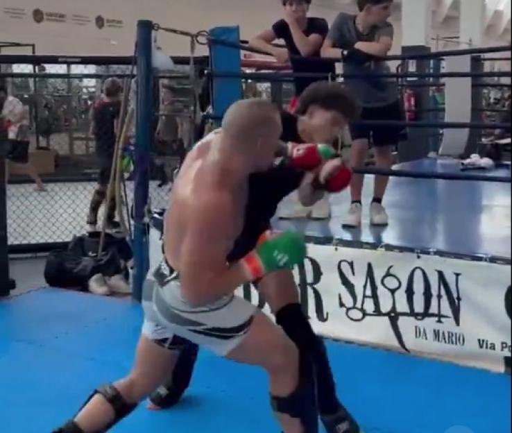 Two mixed martial arts fighters sparring in a cage.