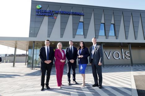 Five people stand in front of Belfast International Airport.