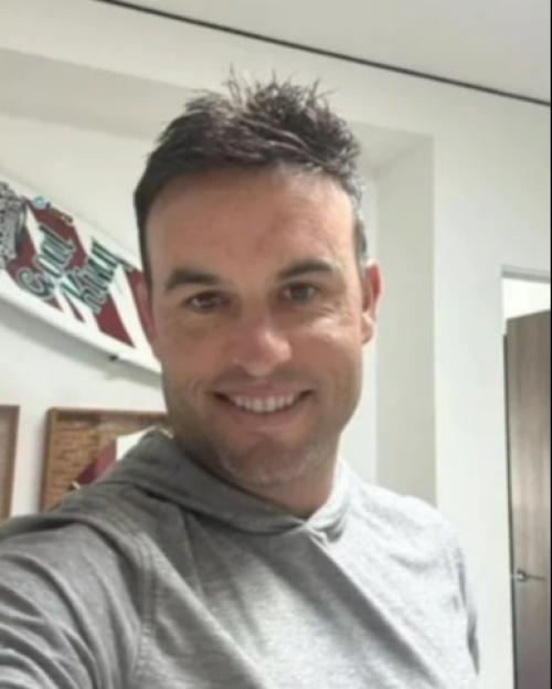 Smiling man in a grey hoodie.
