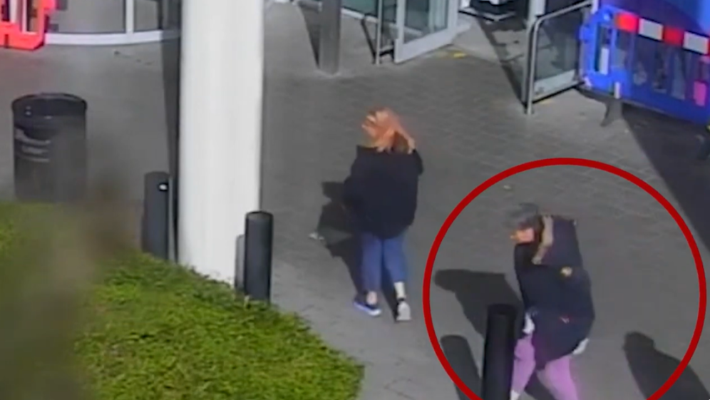 Two women walking away from the camera, one of them circled in red.