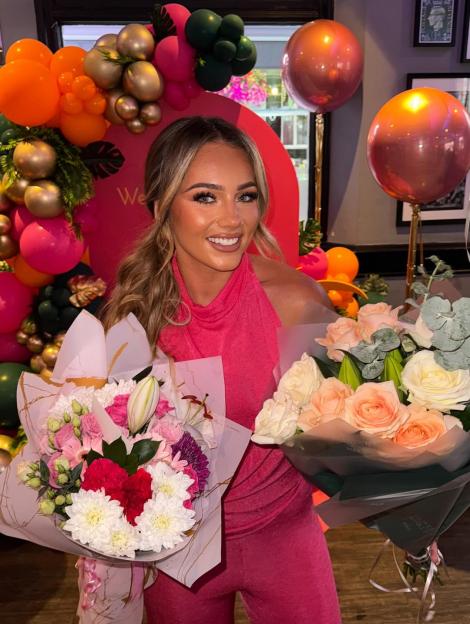 Meg from Love Island holding two bouquets of flowers.