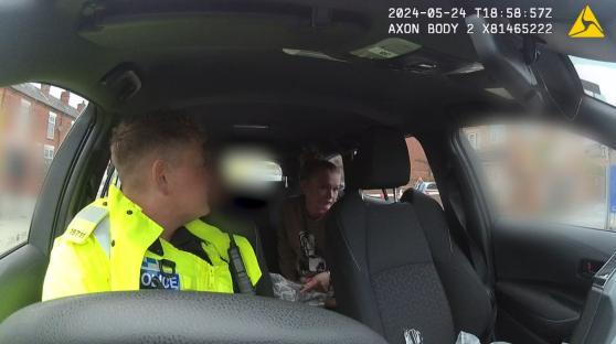Police officer questioning a woman in a car.