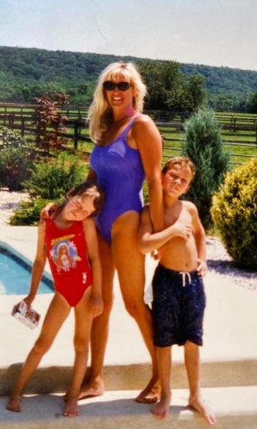 a woman in a bathing suit stands next to two children