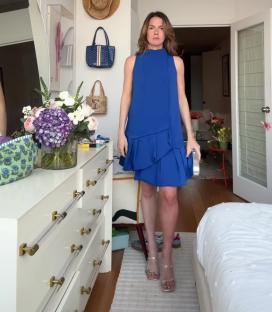 Woman in blue dress realizing one leg is tanner than the other.