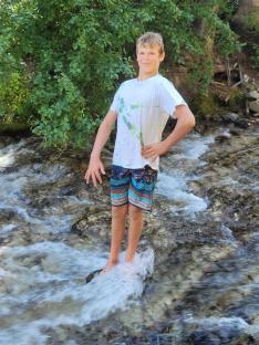 Teenager standing in a stream.