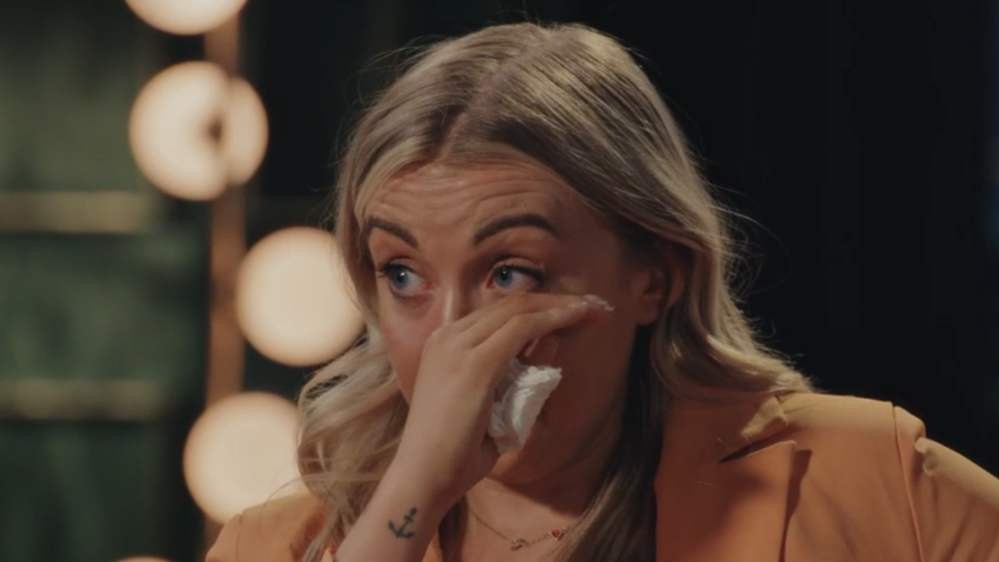 Sarah crying and wiping away tears with a tissue.