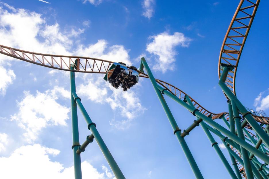 Rollercoaster car with passengers against a blue sky.