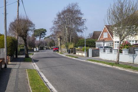 Residential street scene with houses and a red car.