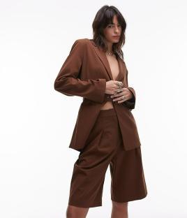 Woman in brown blazer and shorts.